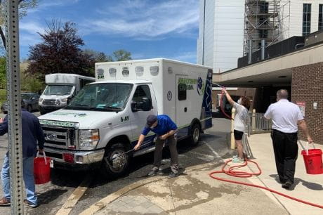 Emergency medicine volunteers wash an ambulance outside of Geisinger Community Medical Center.