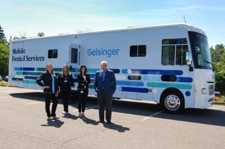 Individuals standing in front of Geisinger's mobile dental services bus