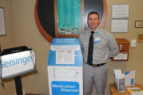 Geisinger pharmacist Shea Payne standing next to the medication takeback box at Geisinger Jersey Shore Hospital