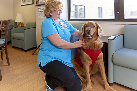 A woman sits with a pet therapy dog.