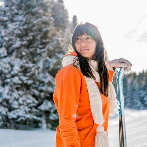 woman in orange jacket with skis