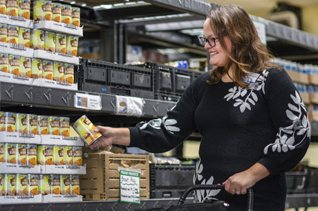 a woman looking at canned goods at the grocery store