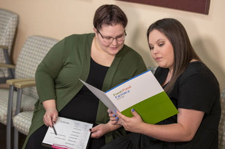 two woman readying fresh food pharmacy information