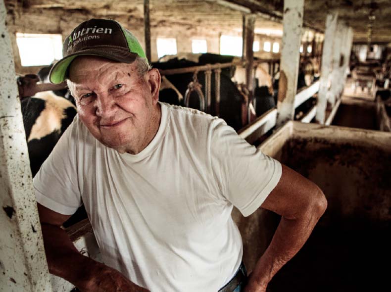 A local dairy farmer takes a moment from his busy day to have a picture taken in the barn.
