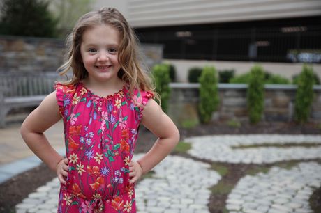 Laila Mattucci stands in a courtyard with hands on her hips, smiling.