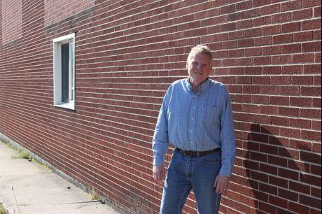 Bob Lepley stands in front of a brick wall, smiling.