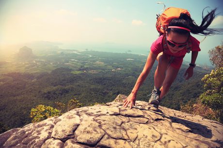 Girl hiking up a mountain on a sunny day, wearing sunglasses.