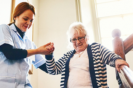 Caregiver helping older woman down the stairs