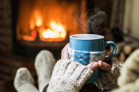 Holding mug by fireplace
