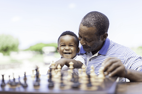 Man playing chess while holding baby