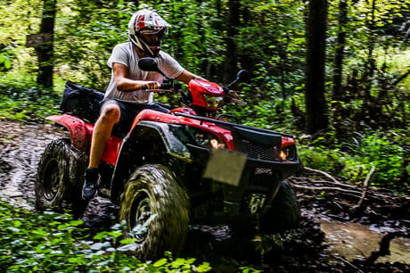 Person driving a ATV with a helment through the woods