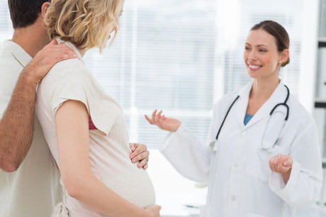 Pregnant woman and partner taking to friendly doctor