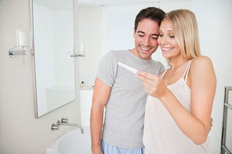 Happy couple in bathroom looking at pregnancy test.