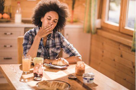 Woman feeling nausea and morning sickness during breakfast time at the kitchen table.