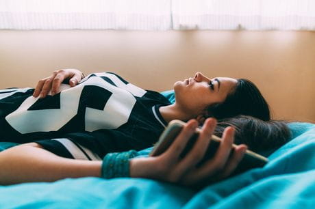 Teen on bed with phone in hand