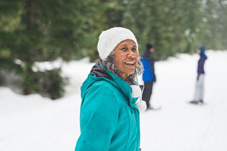 Elderly woman bundled up in the snow to stay warm and help prevent joint pain.