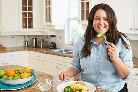 Woman smiling eating broccoli