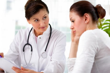 Female doctor reviewing chart with young woman patient