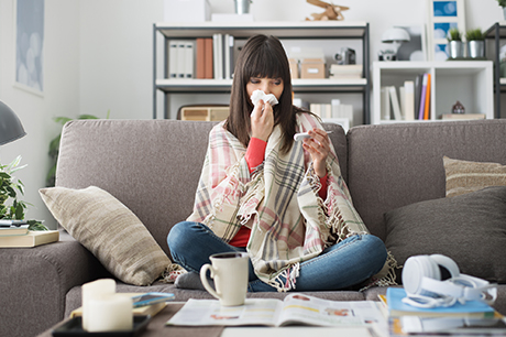 Woman blows nose on the couch