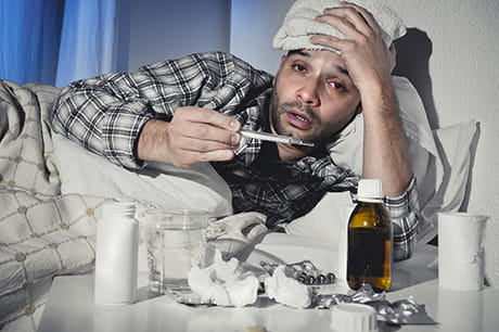 Man with flu symptoms lying in bed.