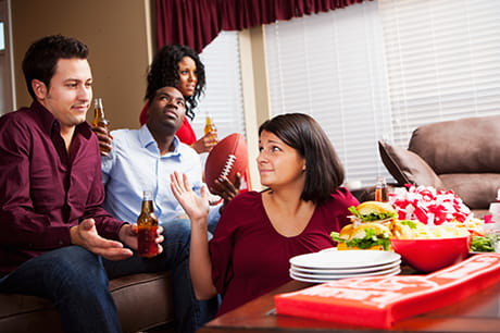 Football fans gather to watch the Super Bowl with snacks.