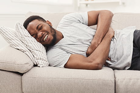Man on couch holding stomach