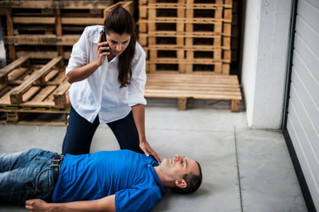 Man laying on the ground with woman on the phone over him.