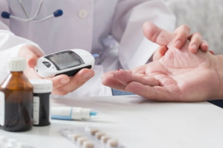 Doctor takes blood sugar level from a patient
