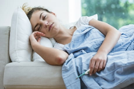 Ill woman sleeps while holding a thermometer 