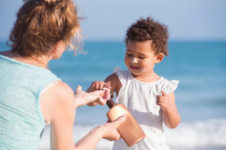 Woman putting sunscreen on a toddler.