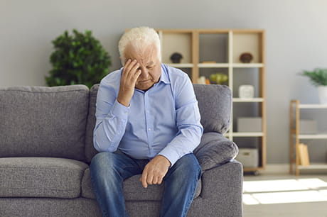 Man with head pain sitting on a couch