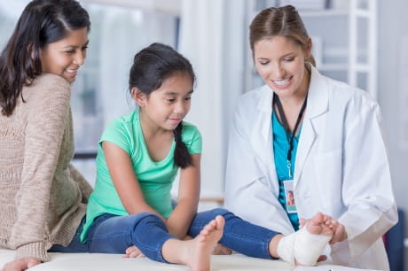 Doctor treating girl who has an ankle injury
