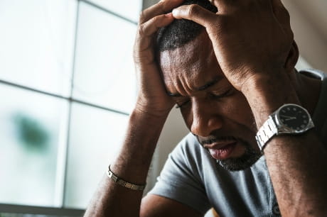 Depressed man sitting and holding his head.