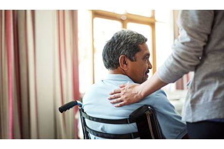 Woman assisting a man in a wheelchair while avoiding caregiver burnout