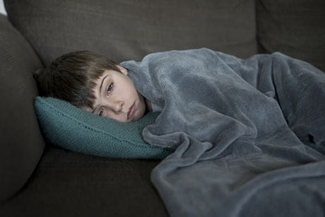 Young boy laying on couch fighting the flu virus