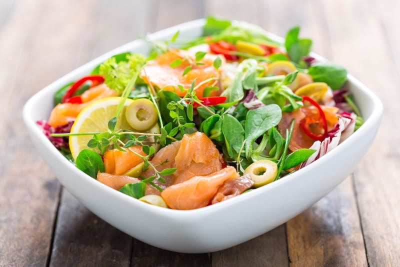 A leafy green salad loaded with fresh salmon, fruit and vegetables.
