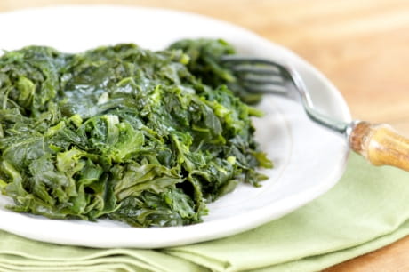 Quick collard greens cooked and served on a plate with a fork.