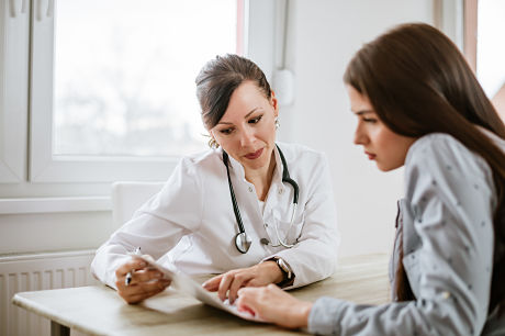 Female doctor talking to young, female patient about colon cancer risks.