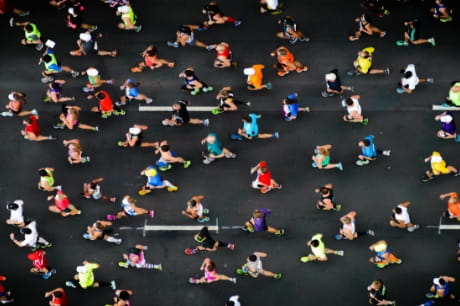 Overhead view of marathon runners on a three-lane street.