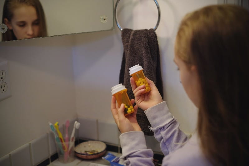 A preteen girl find unsecured prescription drugs in the bathroom