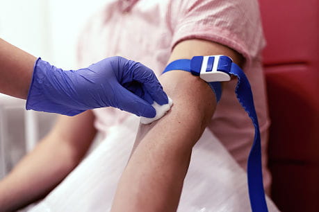 Nurse prepares patient for blood work by cleaning area with alcohol.