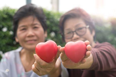 Older woman and adult daughter holding heart figures up in air