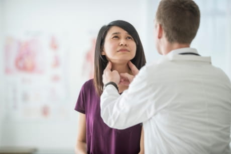 Woman getting her thyroid checked by a male doctor. 