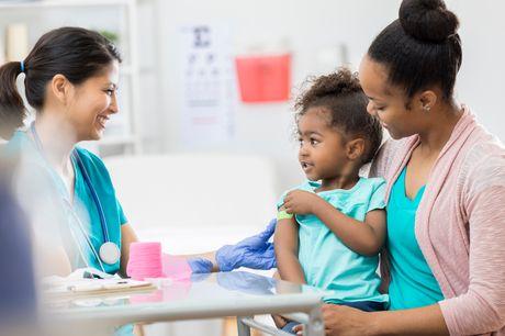 Woman and young daughter with arm boo-boo talking to a smiling nurse