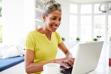 Middle-aged African American woman accessing myGeisinger from a laptop in her kitchen.