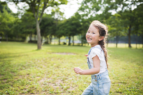 Little girl running and laughing outside during summer.
