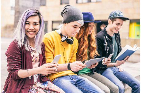 Smiling teens looking at their cell phones