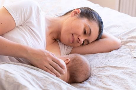 Mother breastfeeding her newborn in the side-lying position.