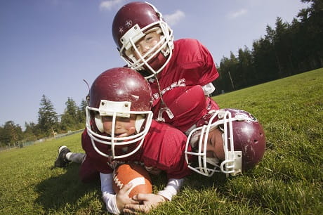 3 young football players in a pile