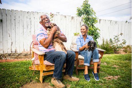 Older couple laughing and playing with their dog. 